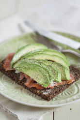 German rye bread with salmon and avocado slices on a plate - SBDF001535