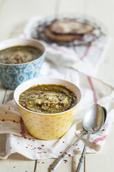 Bowls of Saag spiced with chili flakes on cloth - SBDF001536