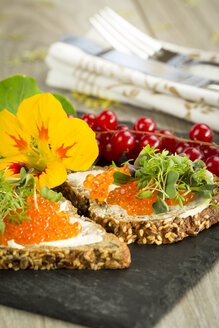 Slices of wholemeal bread with butter and red caviar on slate - JUNF000089