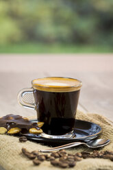 Hausgemachte dunkle Schokolade mit ganzen Nüssen, Kaffeebohnen und einer Tasse Espresso auf Jute - JUNF000113