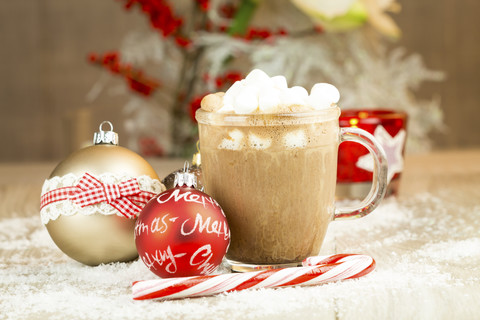 Weihnachtskugeln, Zuckerrohr und ein Glas heiße Schokolade mit Sahne und Marshmallows auf künstlichem Schnee, lizenzfreies Stockfoto