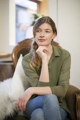 Portrait of relaxed woman sitting on an armchair at living room - NNF000063