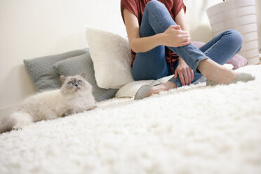 Longhair cat and woman relaxing on a carpet at home - NNF000064