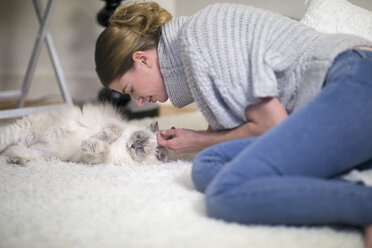 Frau und ihre Langhaarkatze entspannen sich auf dem Teppich zu Hause - NNF000065