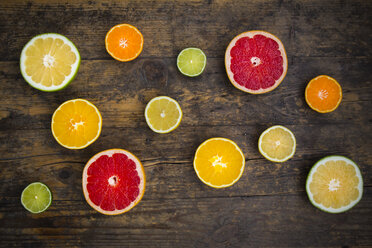 Slices of different citrus fruits on dark wood - LVF002476