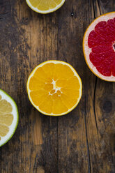 Slices of different citrus fruits on dark wood - LVF002477