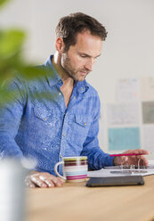 Businessman reading documents in office - UUF002984