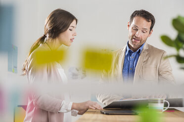 Businessman and busineswoman with file folder talking in office - UUF002991