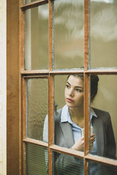 Ernste junge Geschäftsfrau schaut aus dem Fenster - UUF002997
