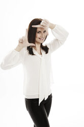 Porträt einer lächelnden jungen Frau, die vor einem weißen Hintergrund ein Handzeichen macht - GDF000649
