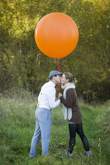 Paar mit Luftballon auf Wiese küssend - JTLF000015