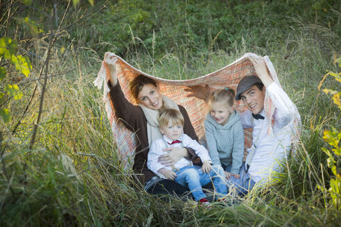 Happy family under blanket on meadow - JTLF000013