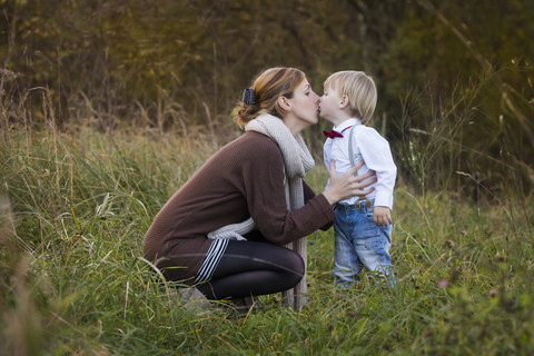 Mutter küsst Sohn auf der Wiese, lizenzfreies Stockfoto