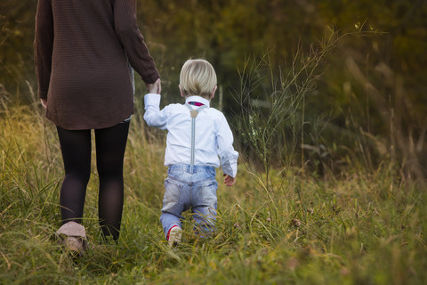 Mother with son walking on meadow stock photo