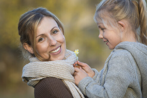 Happy mother and daughter with daisy outdoors - JTLF000003
