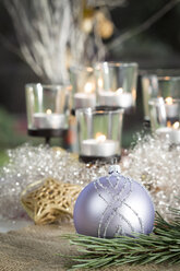 Weihnachtsdekoration, Silberne Christbaumkugel und Kerzen im Hintergrund - JUNF000135