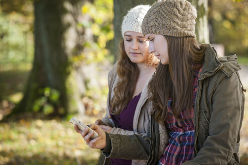 Deutschland, Rheinland-Pfalz, Studentinnen nutzen Smartphone im Freien - PAF001109