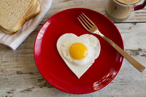 Heart-shaped fried egg on red plate stock photo