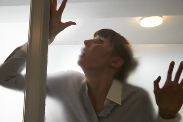Frightened woman behind glass pane - STKF001137