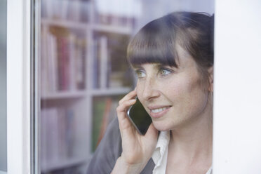 Woman behind glass pane on cell phone - STKF001143