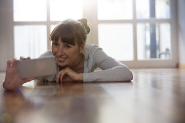 Woman lying on floor taking selfie - STKF001152