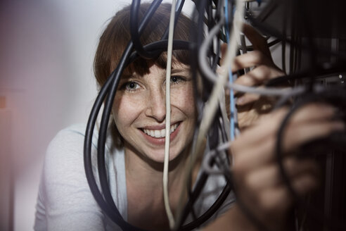 Smiling woman with tangled cables - STKF001154