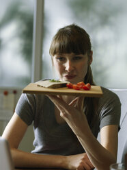 Frau am Schreibtisch hält Tafel mit Snack - STKF001172