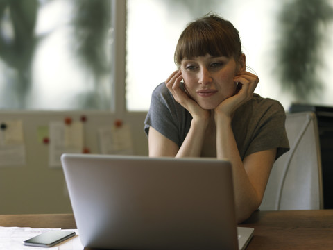 Frau am Schreibtisch mit Laptop, lizenzfreies Stockfoto