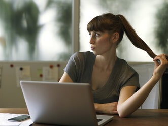 Long-haired woman at desk with laptop - STKF001170