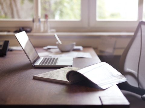 Zeitschrift und Laptop auf dem Schreibtisch, lizenzfreies Stockfoto