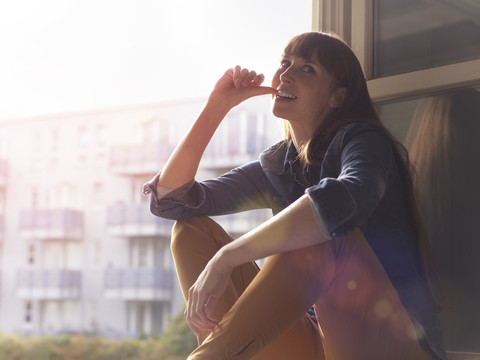 Lächelnde Frau am offenen Fenster, lizenzfreies Stockfoto