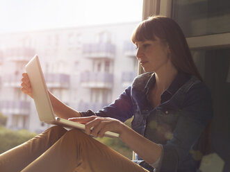 Frau am offenen Fenster mit Laptop - STKF001181