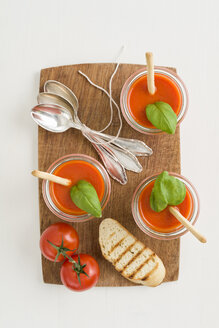 Tomatencremesuppe mit Grissini und Baguette in Gläsern auf einem Schneidebrett aus Holz - ECF001626