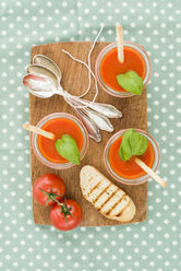 Tomato cream soup with grissini and baguette in glasses on wooden chopping board - ECF001627