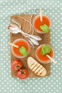 Tomatencremesuppe mit Grissini und Baguette in Gläsern auf einem Schneidebrett aus Holz - ECF001627