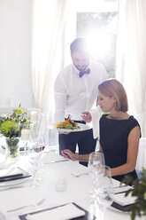 Kellner serviert einer Frau in einem eleganten Restaurant das Abendessen - WESTF020417