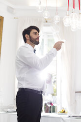 Elegant waiter in restaurant examining wine glass - WESTF020419