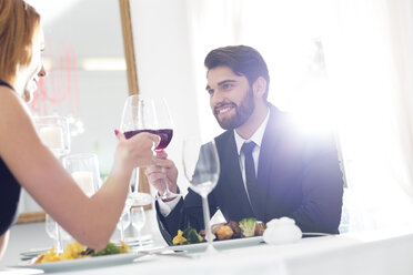 Elegant couple toasting wine glasses in restaurant - WESTF020425