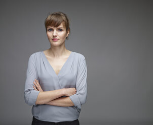 Portrait of young woman with crossed arms in front of grey background - RH000456