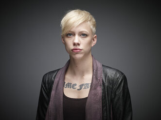 Portrait of blond young woman with tatoo in front of grey background - RH000462