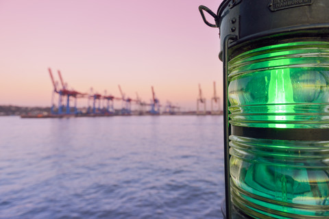 Deutschland, Hamburg, Blick auf den Hafen in der Dämmerung mit Schiffslicht im Vordergrund, lizenzfreies Stockfoto