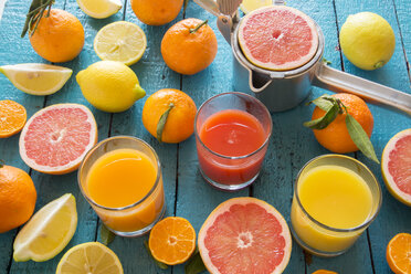 Gläser mit Orangensaft, Grapefruitsaft und Multivitaminsaft, Saftpresse und Früchte auf Holz - SARF001197