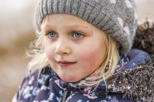 Porträt eines blonden kleinen Mädchens mit Wollmütze und Winterjacke - TCF004478