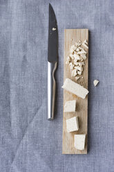 Tofu in Scheiben geschnitten auf Holzbrett und Küchenmesser auf Tuch - MYF000784