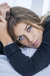 Porträt einer blonden Frau mit blauen Augen auf dem Bett liegend, Nahaufnahme - TCF004490