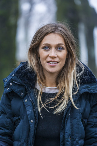 Porträt einer lächelnden blonden Frau mit blauem Anorak, lizenzfreies Stockfoto