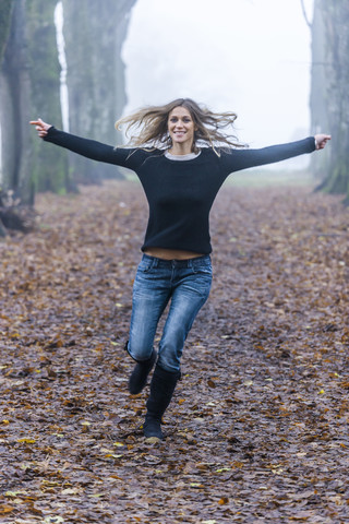 Woman with outstretched armes running along a forest track stock photo