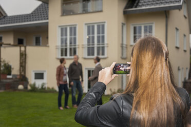 Teenagerin fotografiert ihre Eltern und den Makler vor einem Wohnhaus - PAF001118