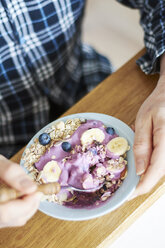 Mann im Pyjama isst Müsli mit Sojajoghurt, Blaubeeren und Banane - HAWF000546