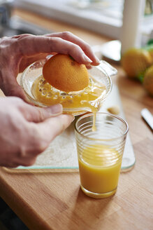 Mann gießt frisch gepressten Orangensaft in ein Glas - HAWF000549